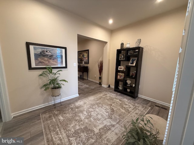 hallway featuring visible vents, wood finished floors, and baseboards