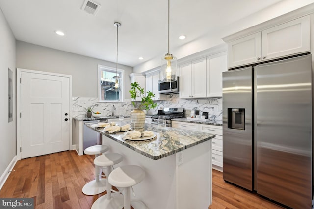 kitchen with light wood finished floors, visible vents, tasteful backsplash, and appliances with stainless steel finishes