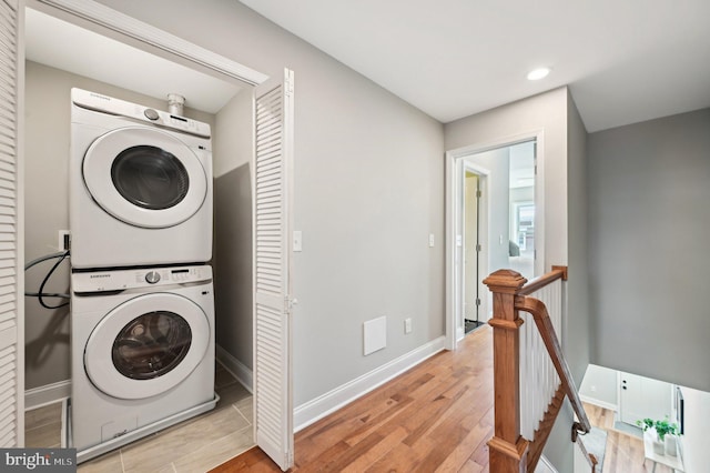 clothes washing area featuring baseboards, laundry area, recessed lighting, stacked washer / drying machine, and light wood-type flooring