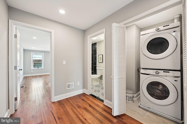 laundry area with visible vents, laundry area, wood finished floors, and stacked washer and dryer