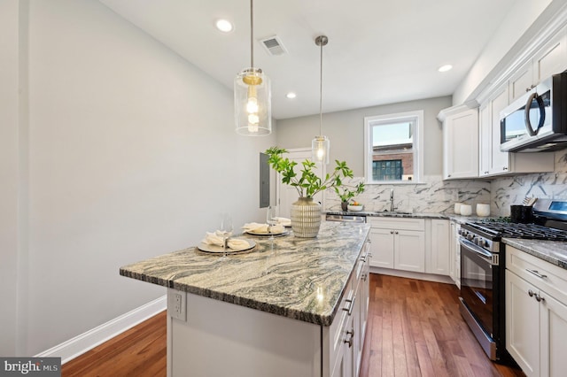 kitchen featuring dark wood-style floors, visible vents, a sink, stainless steel appliances, and a center island