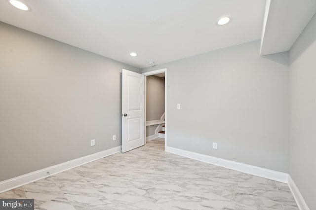 empty room with recessed lighting, marble finish floor, and baseboards