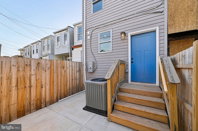 doorway to property featuring fence and central AC