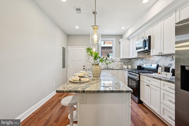 kitchen featuring visible vents, dark wood-style flooring, stainless steel appliances, white cabinetry, and tasteful backsplash