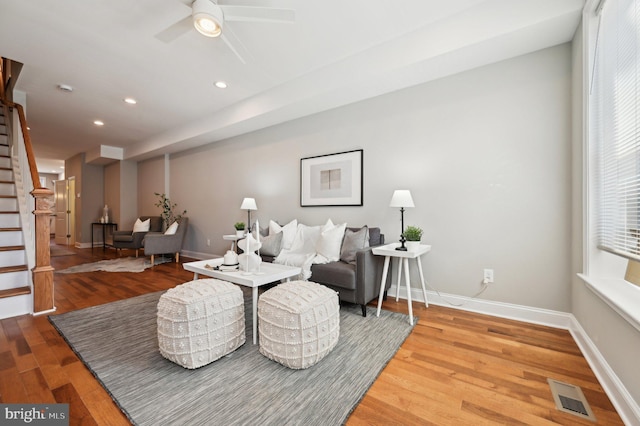 living room with visible vents, wood finished floors, stairway, baseboards, and ceiling fan