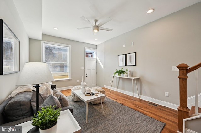 living area with visible vents, baseboards, ceiling fan, and wood finished floors