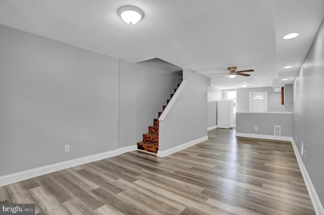 unfurnished living room featuring stairs, baseboards, and wood finished floors