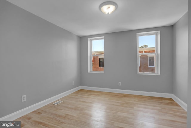 empty room with baseboards, visible vents, a wealth of natural light, and light wood-type flooring