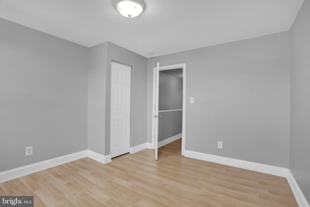 unfurnished bedroom with light wood-style flooring, baseboards, and a closet