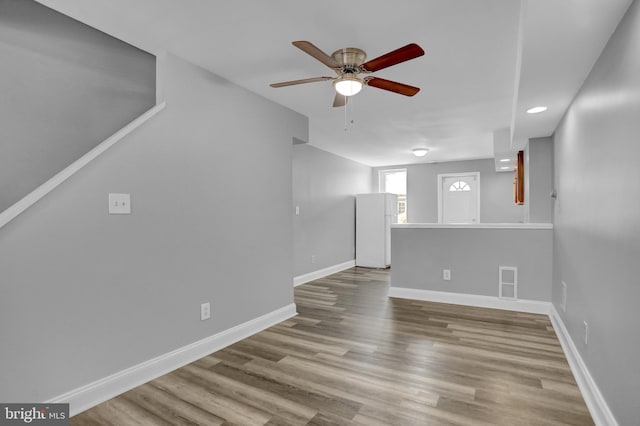 unfurnished living room featuring visible vents, a ceiling fan, baseboards, and wood finished floors