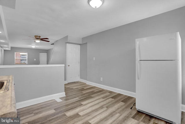 kitchen featuring wood finished floors, baseboards, freestanding refrigerator, ceiling fan, and light countertops