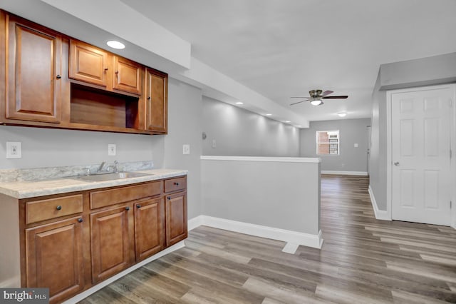 kitchen with ceiling fan, light countertops, wood finished floors, and a sink