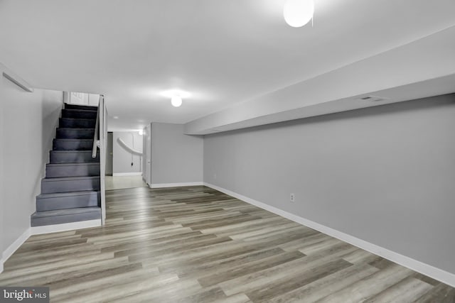 finished below grade area featuring visible vents, light wood-style flooring, stairs, and baseboards