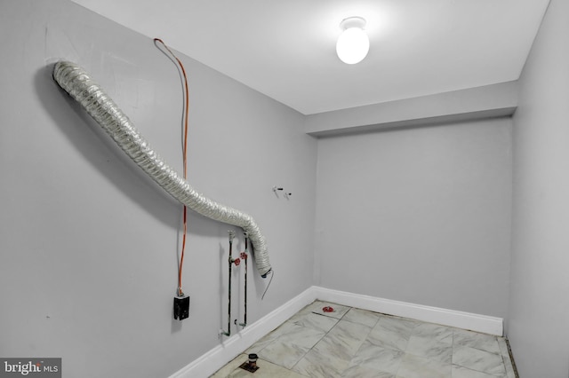 clothes washing area with marble finish floor and baseboards