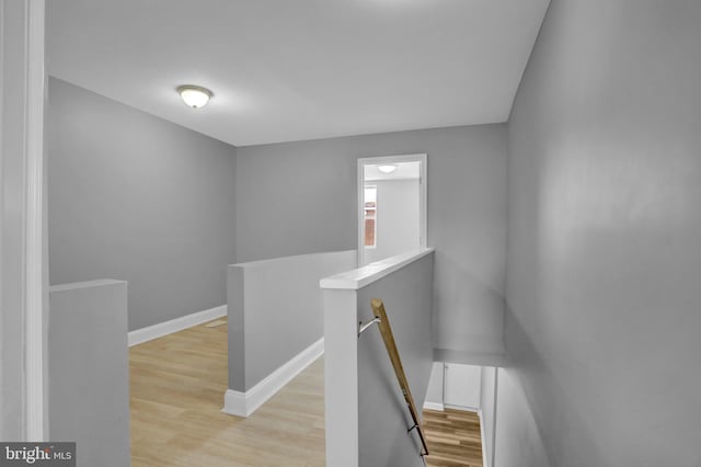 corridor featuring wood finished floors, an upstairs landing, and baseboards