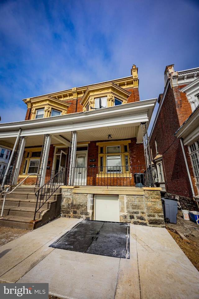 townhome / multi-family property with stone siding, a porch, and driveway