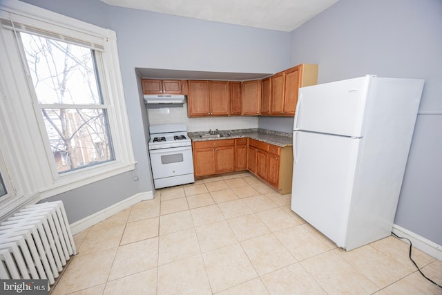 kitchen featuring white appliances, radiator, light tile patterned flooring, a sink, and under cabinet range hood