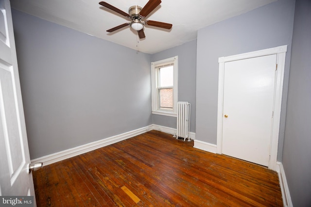 spare room featuring hardwood / wood-style flooring, radiator, baseboards, and ceiling fan