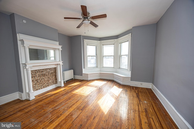 unfurnished living room featuring ceiling fan, radiator heating unit, baseboards, and hardwood / wood-style floors