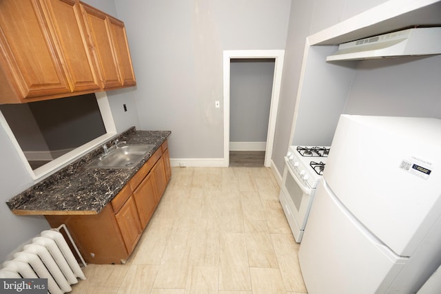 kitchen featuring a sink, dark stone counters, white appliances, radiator, and exhaust hood