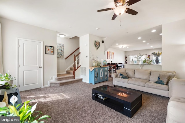 carpeted living area with stairway, baseboards, visible vents, recessed lighting, and ceiling fan