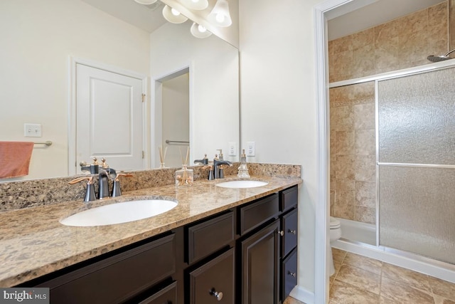 bathroom with double vanity, a shower stall, toilet, and a sink