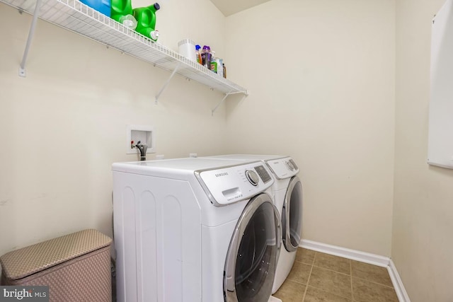 clothes washing area with washer and dryer, laundry area, light tile patterned floors, and baseboards