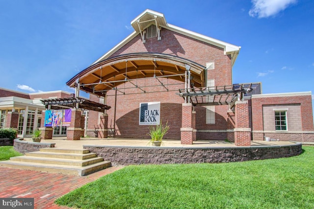 back of property with a yard, brick siding, and a pergola