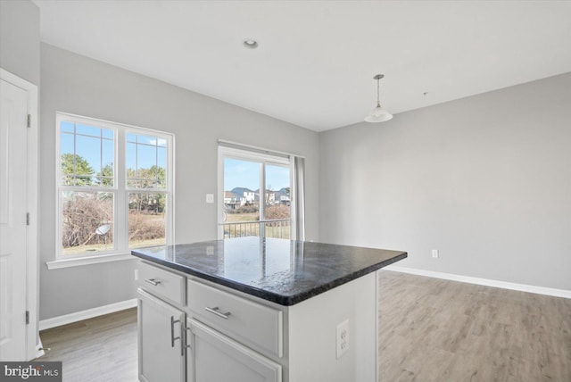 kitchen with a kitchen island, white cabinets, baseboards, and light wood-style floors