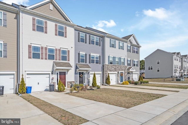 townhome / multi-family property with driveway, a residential view, and stone siding