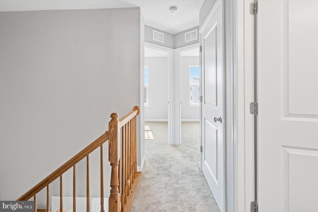 hall with light colored carpet, an upstairs landing, visible vents, and baseboards