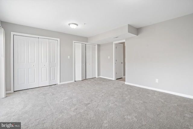 unfurnished bedroom featuring baseboards, carpet, and multiple closets