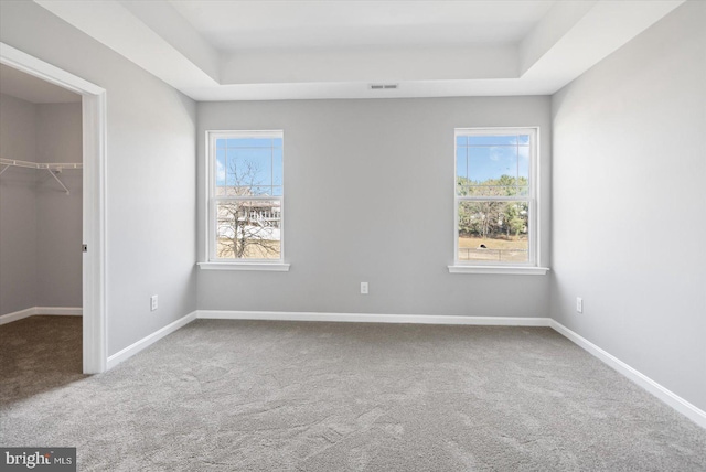 unfurnished room with carpet flooring, a raised ceiling, and baseboards