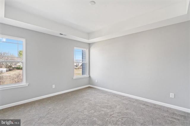 carpeted spare room featuring visible vents, a healthy amount of sunlight, and baseboards