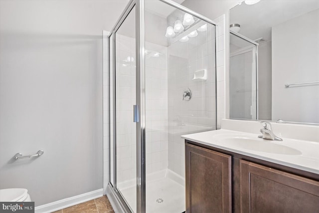 bathroom with a shower stall, toilet, vanity, and baseboards