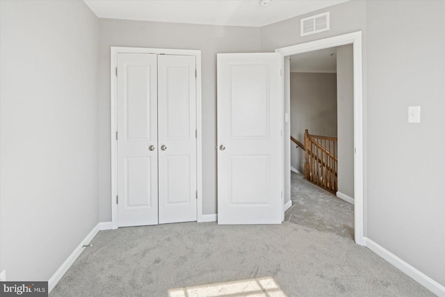 unfurnished bedroom with a closet, visible vents, baseboards, and carpet floors