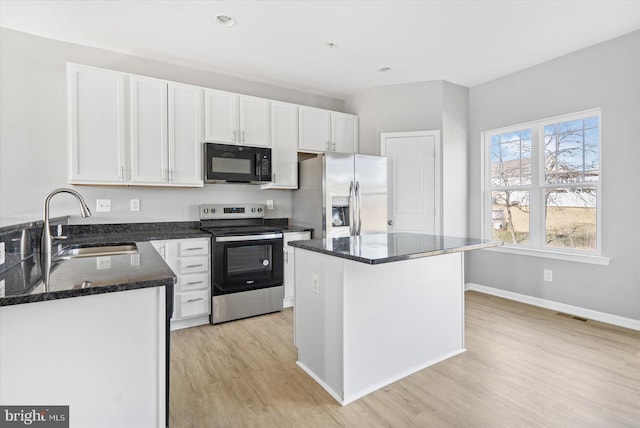 kitchen featuring dark stone countertops, white cabinets, stainless steel appliances, and a sink