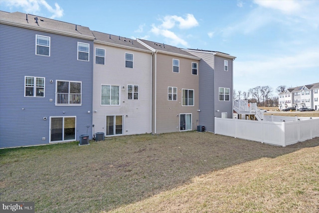 rear view of house with a lawn, central AC, and fence