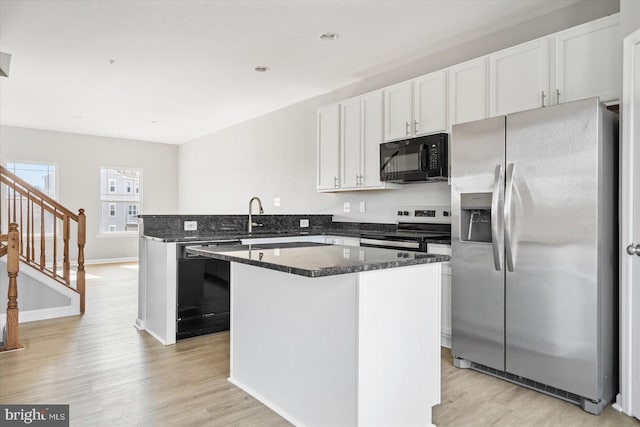 kitchen featuring white cabinetry, black appliances, a peninsula, and light wood finished floors