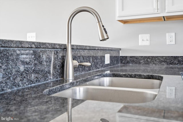 interior details with dark countertops, white cabinetry, and a sink