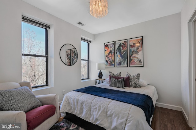 bedroom with visible vents, multiple windows, baseboards, and wood finished floors