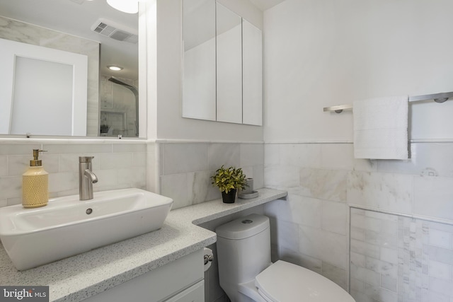 bathroom featuring visible vents, toilet, tile walls, a shower, and vanity