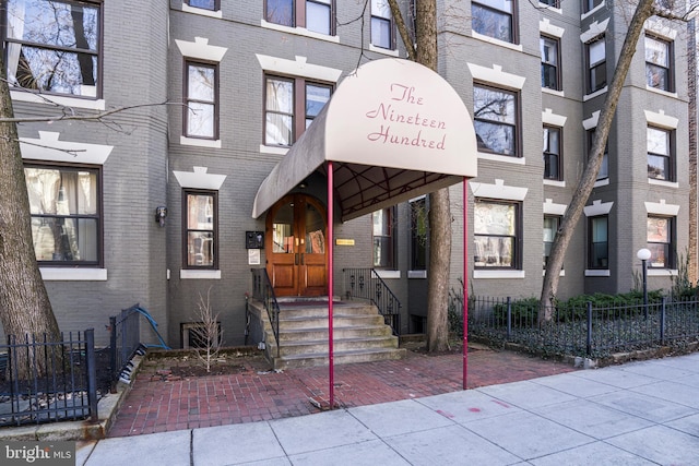 view of exterior entry with brick siding and fence