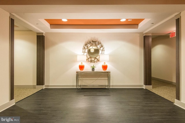 hall featuring recessed lighting, a tray ceiling, baseboards, and dark wood finished floors