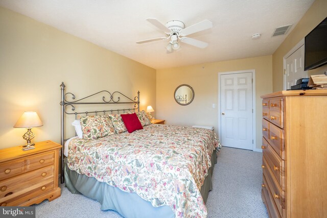carpeted bedroom with a ceiling fan and visible vents