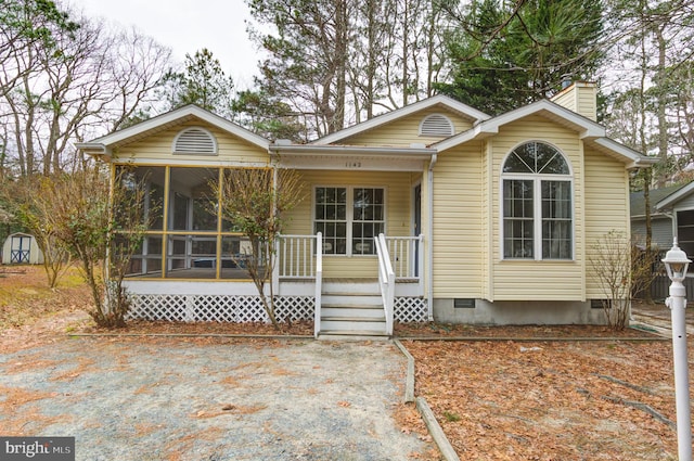 view of front of house featuring crawl space, covered porch, a chimney, and a sunroom