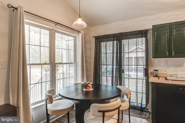 dining area with wood finished floors and vaulted ceiling