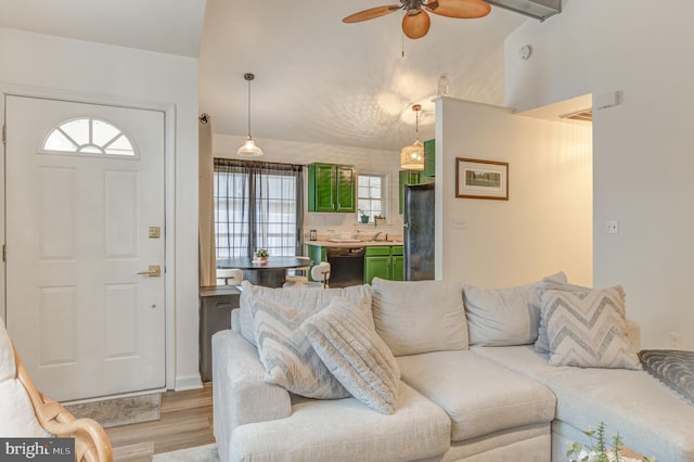 living area featuring lofted ceiling, light wood-style floors, and ceiling fan