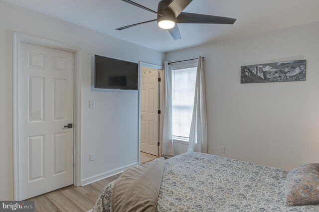 bedroom featuring light wood-style flooring, a ceiling fan, and baseboards