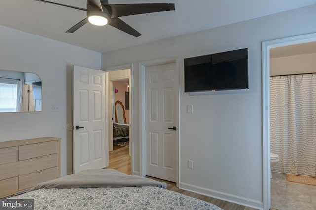 unfurnished bedroom with ceiling fan, ensuite bath, baseboards, and wood finished floors